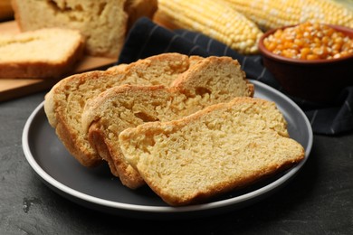 Photo of Freshly baked cornbread, cobs and seeds on black table, closeup