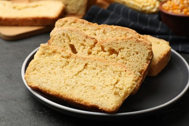 Photo of Pieces of freshly baked cornbread on black table, closeup