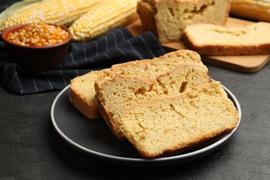 Photo of Freshly baked cornbread, cobs and seeds on black table, closeup
