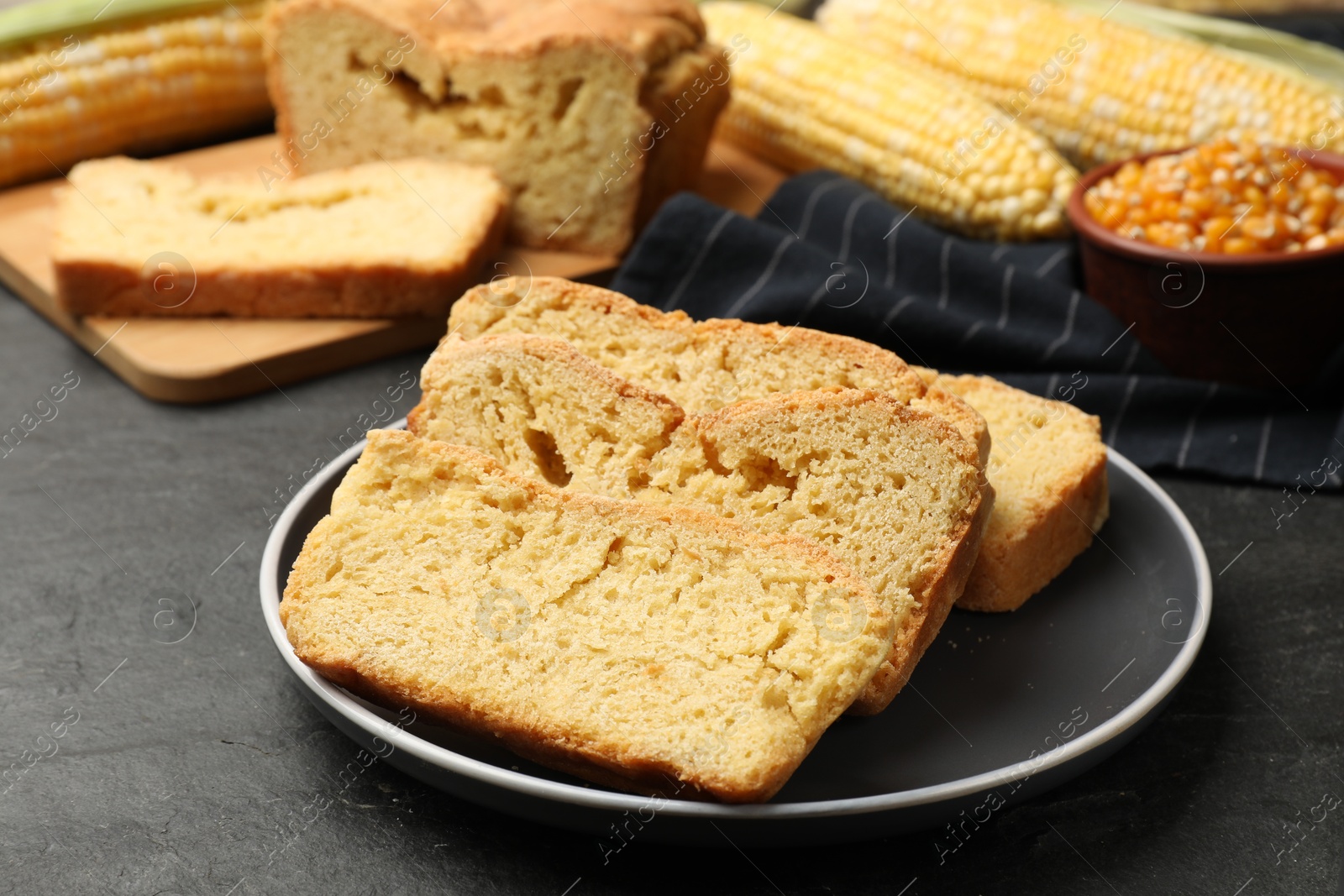 Freshly baked cornbread, cobs and seeds on black table, closeup Photo of Freshly baked cornbread, cobs and seeds on black table, closeup