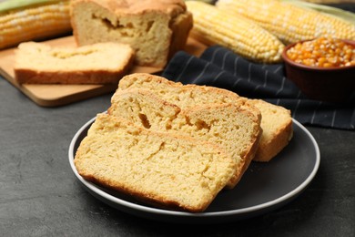 Photo of Freshly baked cornbread, cobs and seeds on black table, closeup