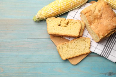 Photo of Freshly baked cornbread and cobs on light blue wooden table, flat lay. Space for text