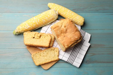 Photo of Freshly baked cornbread and cobs on light blue wooden table, flat lay