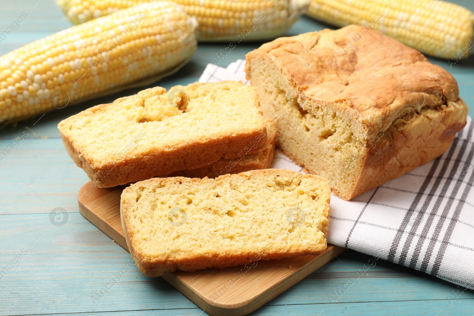 Photo of Freshly baked cornbread and cobs on light blue wooden table, closeup