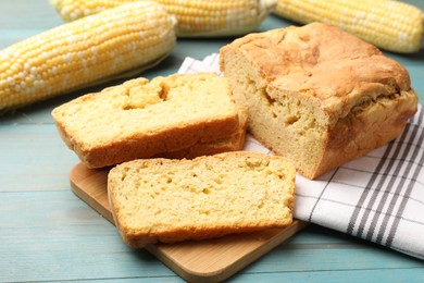 Photo of Freshly baked cornbread and cobs on light blue wooden table, closeup