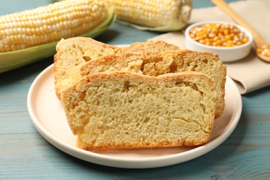 Photo of Freshly baked cornbread, cobs and seeds on light blue wooden table, closeup