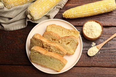 Photo of Freshly baked cornbread, cobs and flour on wooden table, flat lay