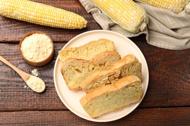 Photo of Freshly baked cornbread, cobs and flour on wooden table, flat lay