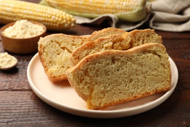 Photo of Freshly baked cornbread, cobs and flour on wooden table, closeup