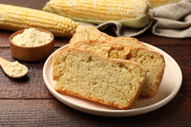 Photo of Freshly baked cornbread, cobs and flour on wooden table, closeup