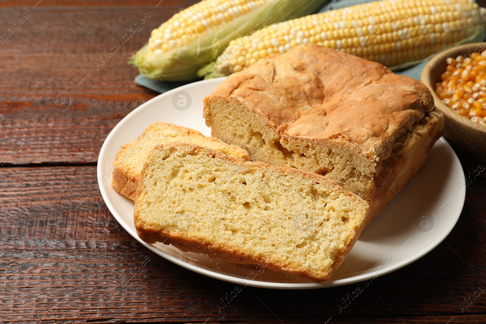 Photo of Freshly baked cornbread, cobs and seeds on wooden table, closeup