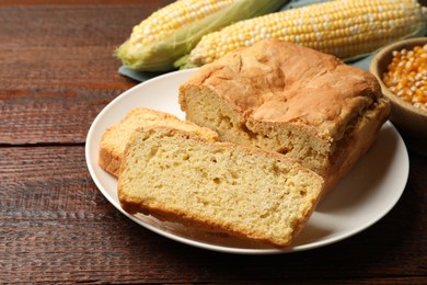 Photo of Freshly baked cornbread, cobs and seeds on wooden table, closeup