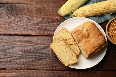 Photo of Freshly baked cornbread, cobs and seeds on wooden table, flat lay. Space for text