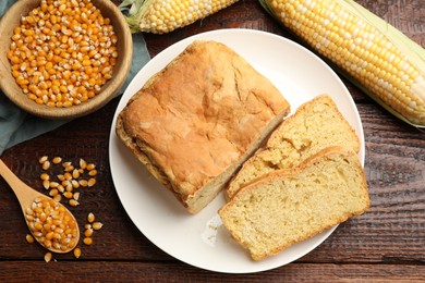 Photo of Freshly baked cornbread, cobs and seeds on wooden table, flat lay