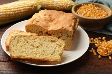 Photo of Freshly baked cornbread, cobs and seeds on wooden table, closeup