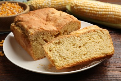 Photo of Freshly baked cornbread, cobs and seeds on wooden table, closeup