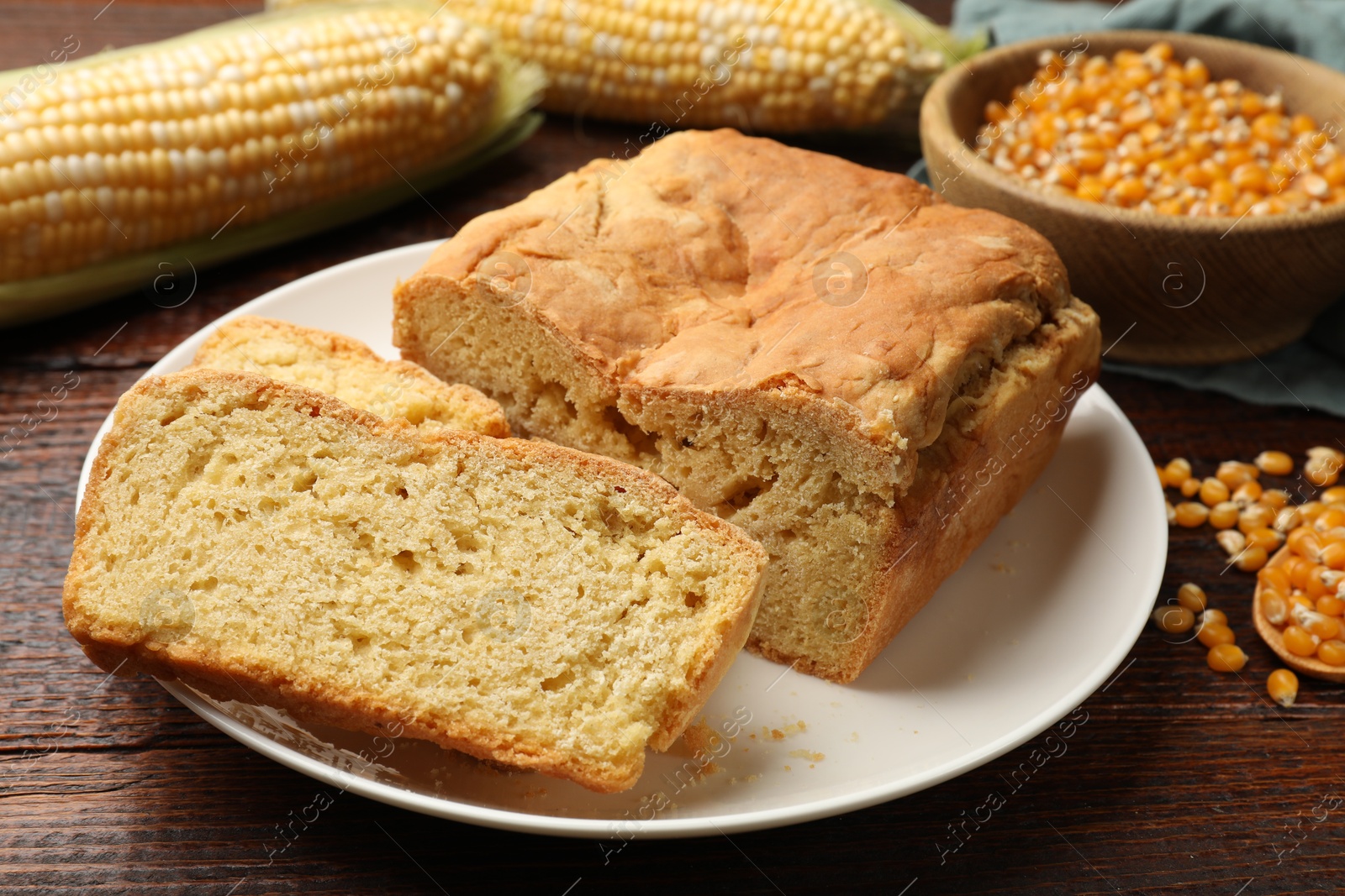Photo of Freshly baked cornbread, cobs and seeds on wooden table, closeup