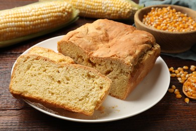 Photo of Freshly baked cornbread, cobs and seeds on wooden table, closeup