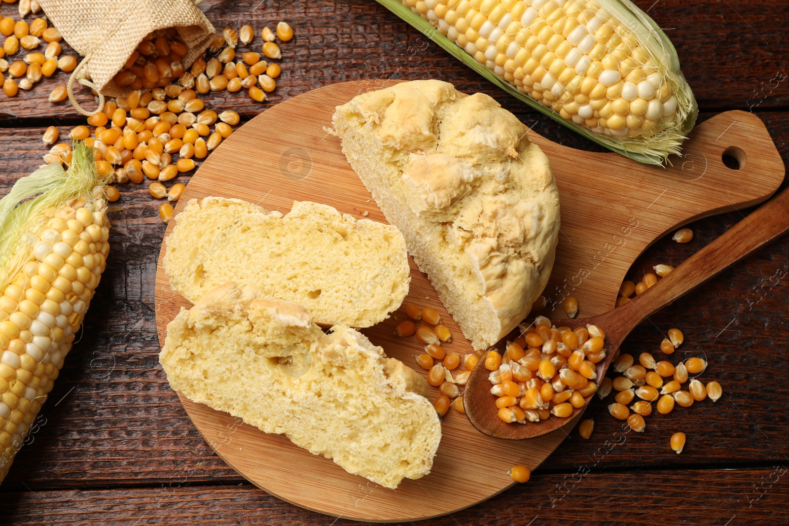 Freshly baked cornbread, cobs and seeds on wooden table, flat lay Photo of Freshly baked cornbread, cobs and seeds on wooden table, flat lay