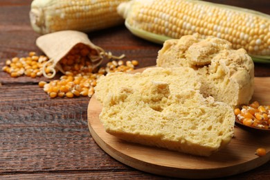 Photo of Freshly baked cornbread, cobs and seeds on wooden table, closeup. Space for text