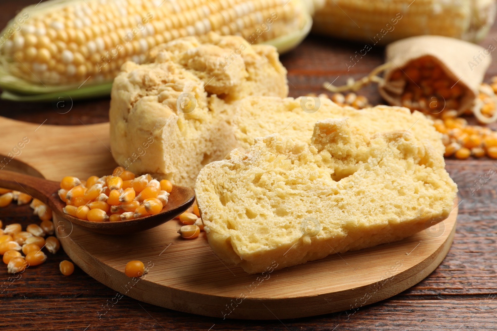 Photo of Freshly baked cornbread, cobs and seeds on wooden table, closeup