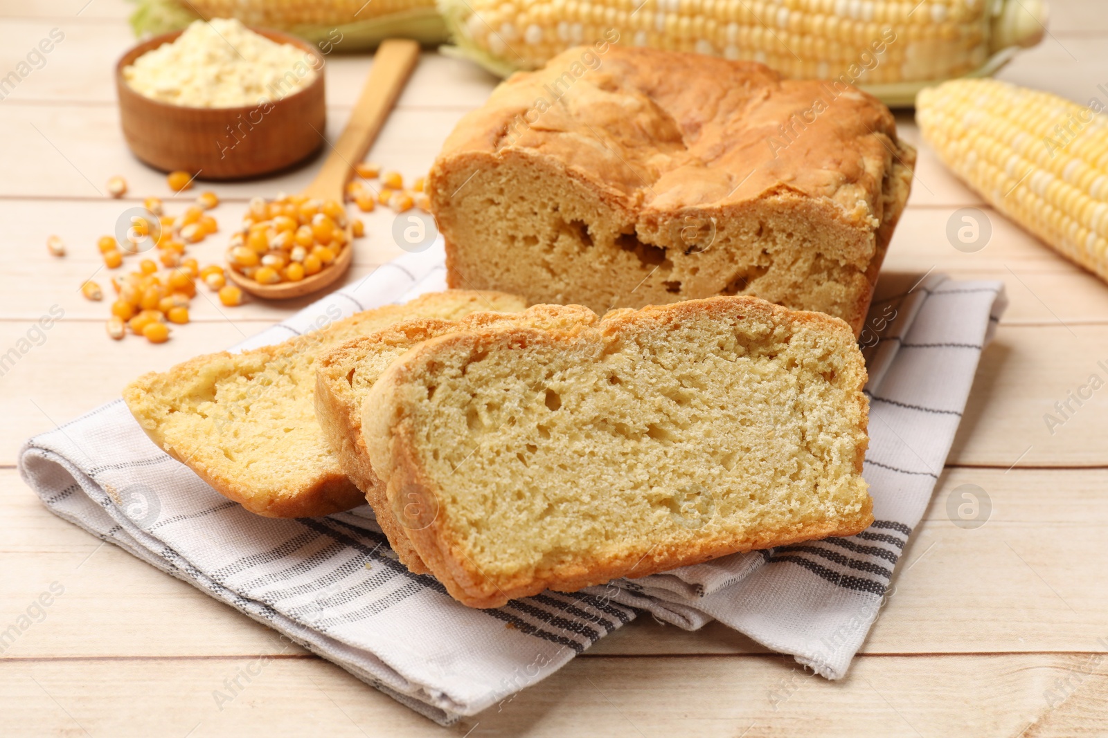 Photo of Freshly baked cornbread, cobs and seeds on wooden table, closeup