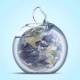 Image of Save water concept. Earth inside aquarium bowl with splashing water against light blue background