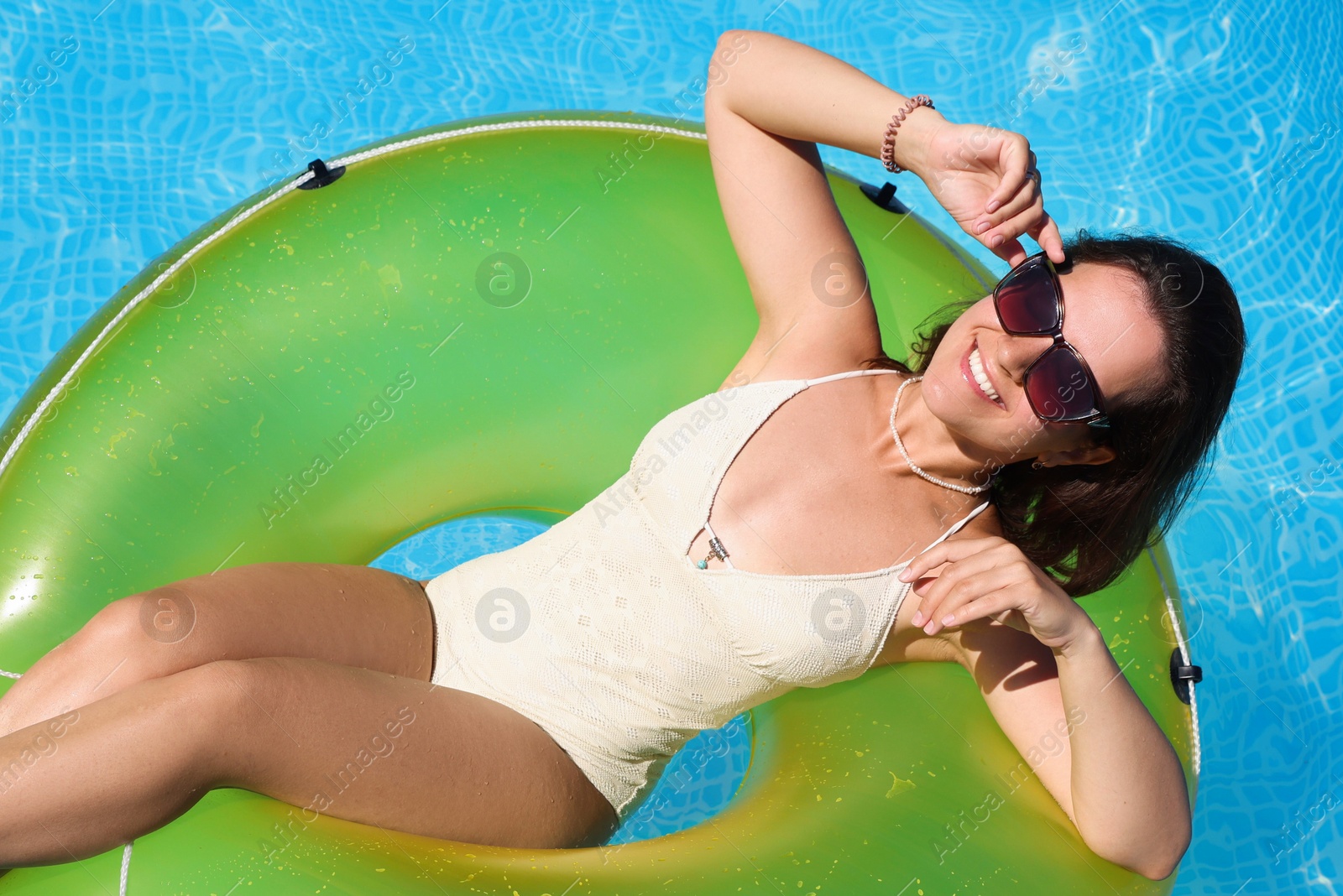 Photo of Woman on inflatable ring relaxing in swimming pool, above view