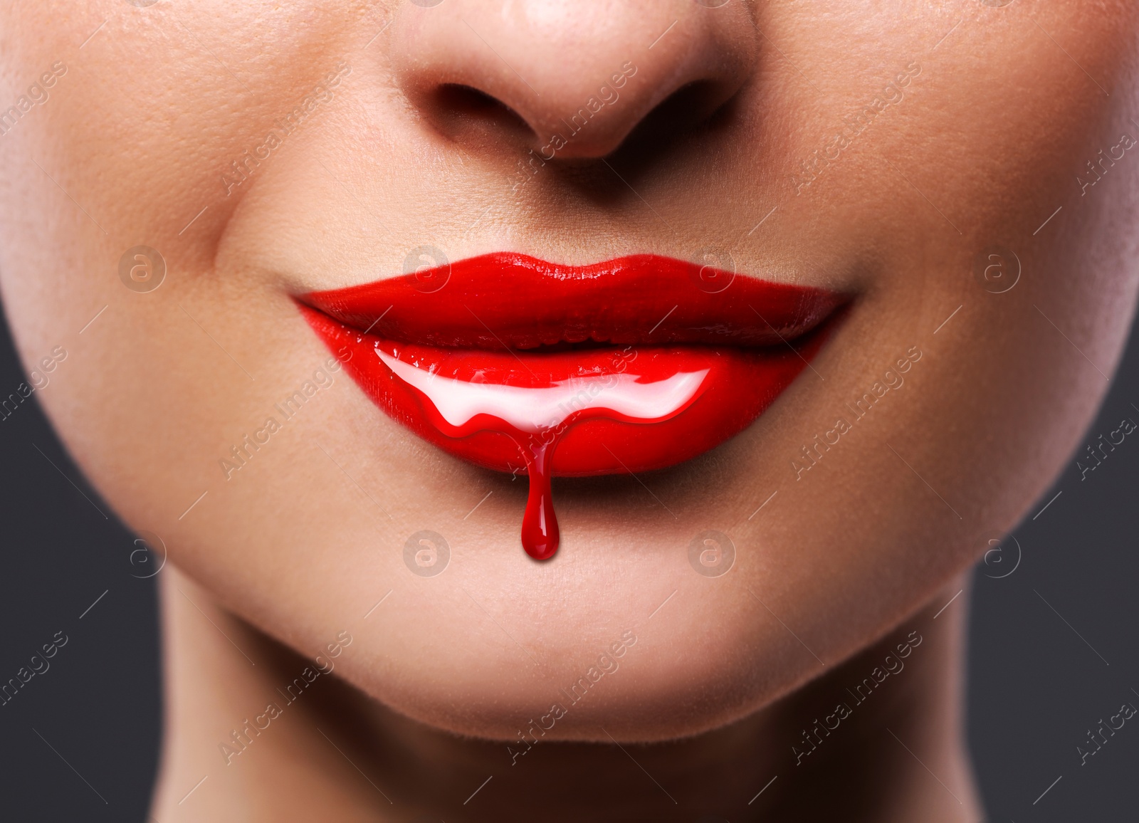 Image of Red liquid lipstick dripping from woman's lip, closeup