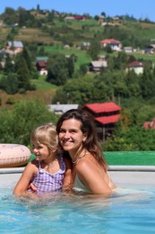 Photo of Happy mother and daughter in swimming pool at resort