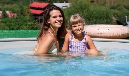 Photo of Happy mother and daughter in swimming pool at resort