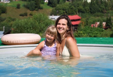 Photo of Happy mother and daughter in swimming pool at resort