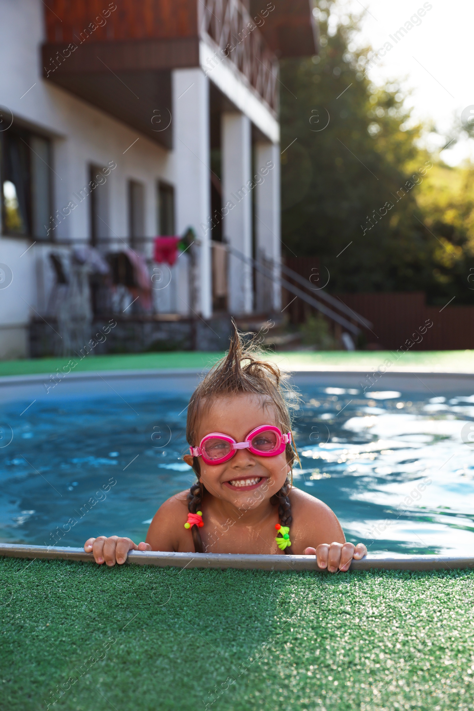 Photo of Cute little girl wearing googles in swimming pool at resort