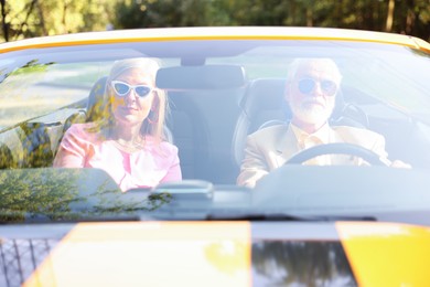 Photo of Senior couple enjoying cabriolet ride in city, view from outdoors