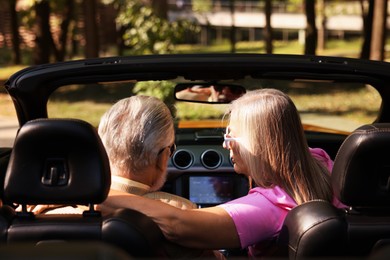 Photo of Senior couple enjoying cabriolet ride in city, back view