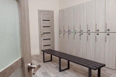 Photo of Wooden bench and lockers in changing room interior