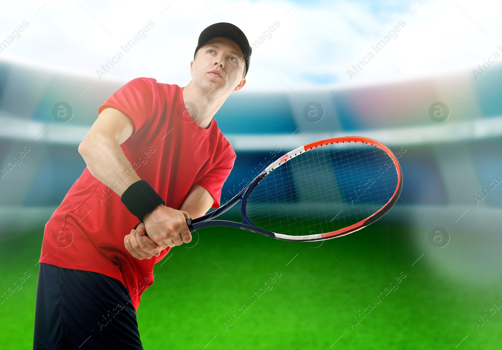 Image of Man with racket playing tennis at stadium, low angle view