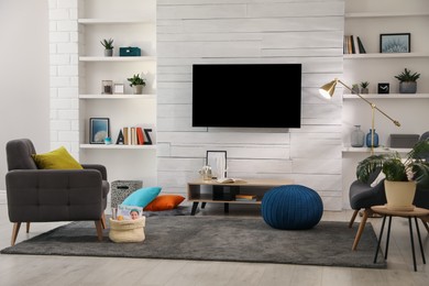 Photo of Cozy room interior with stylish furniture, decor and modern TV set