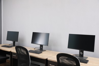 Photo of Open office interior. Modern workplaces with computers near light grey wall