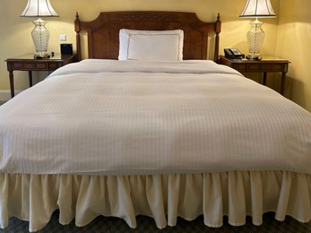 Photo of Comfortable large bed and modern furniture in stylish hotel room
