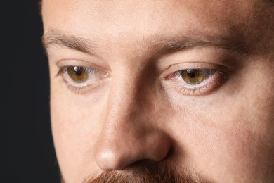 Photo of Man with beautiful eyes on black background, closeup