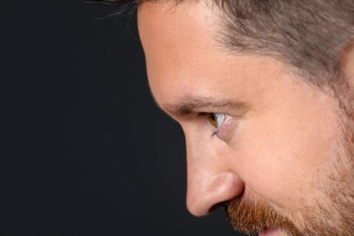 Photo of Man with beautiful eyes on black background, closeup. Space for text