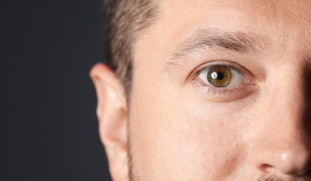 Photo of Man with beautiful eyes on black background, closeup. Space for text