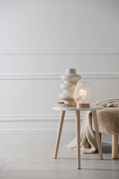 Photo of Stylish lamp and vase on white table indoors, space for text