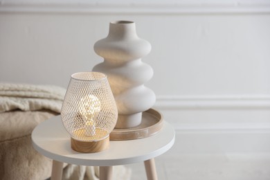 Photo of Stylish lamp and vase on white table indoors, space for text
