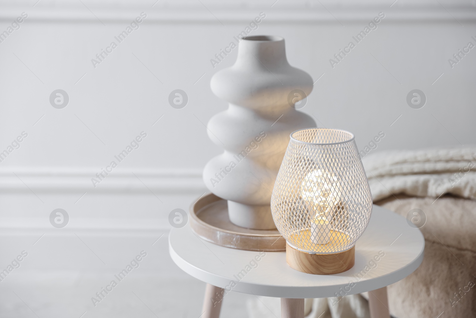 Photo of Stylish lamp and vase on white table indoors, space for text