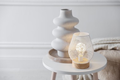 Photo of Stylish lamp and vase on white table indoors, space for text
