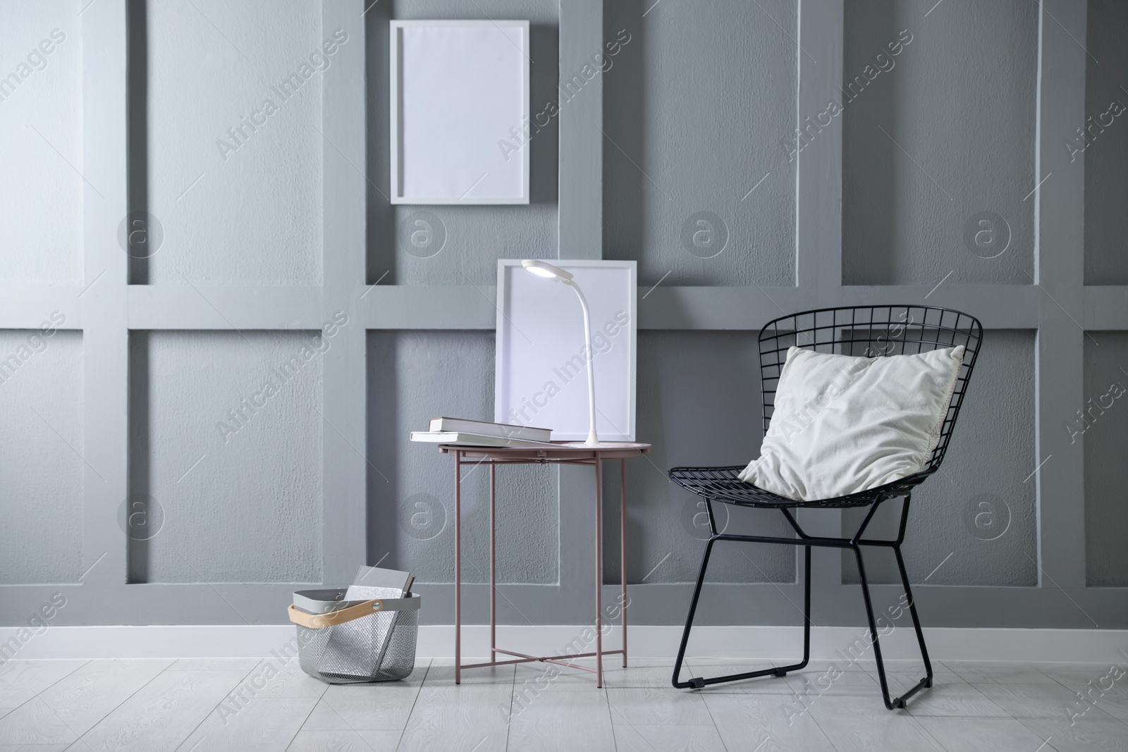 Photo of Stylish lamp and books on table near armchair indoors