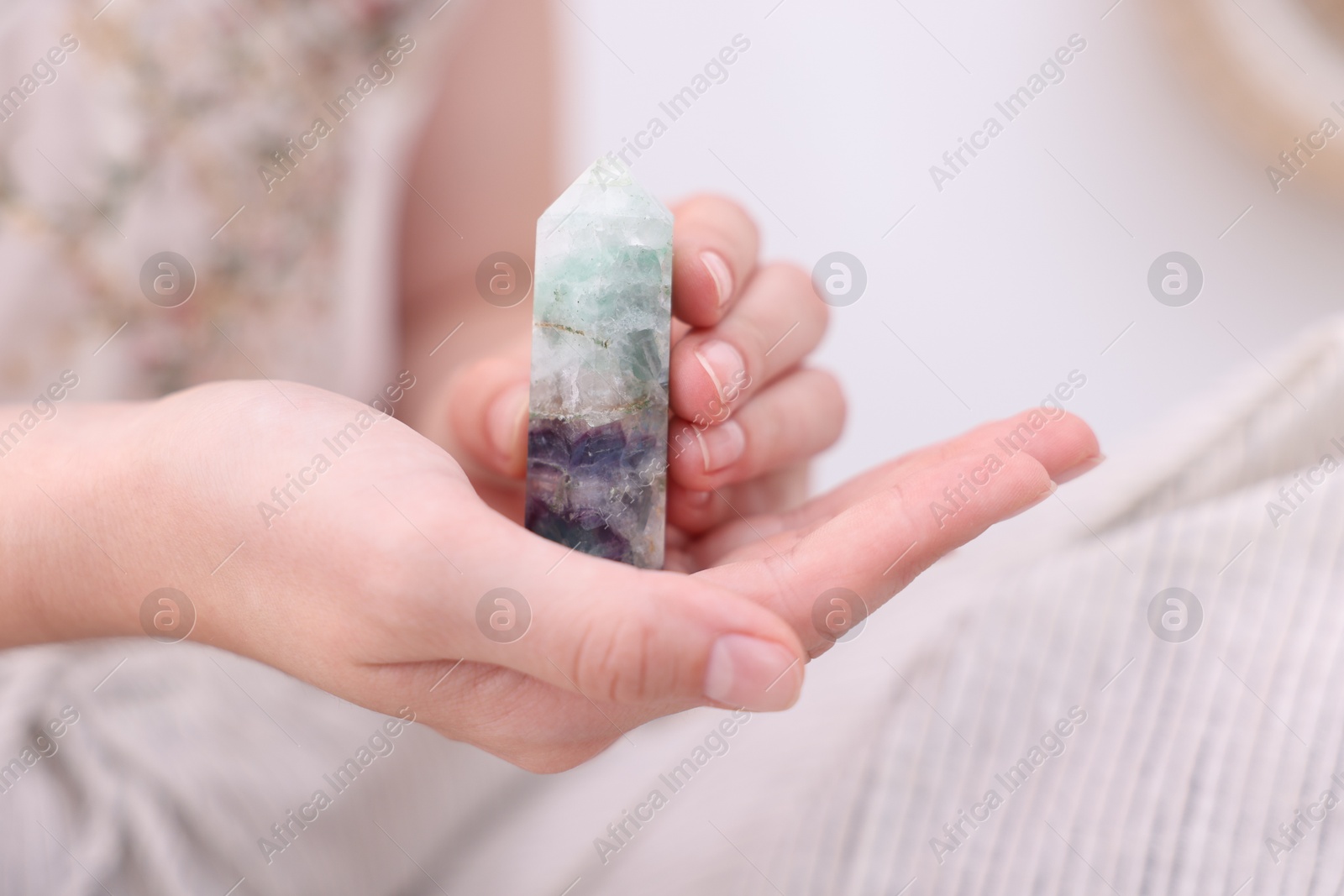 Photo of Woman with beautiful fluorite gemstone indoors, closeup