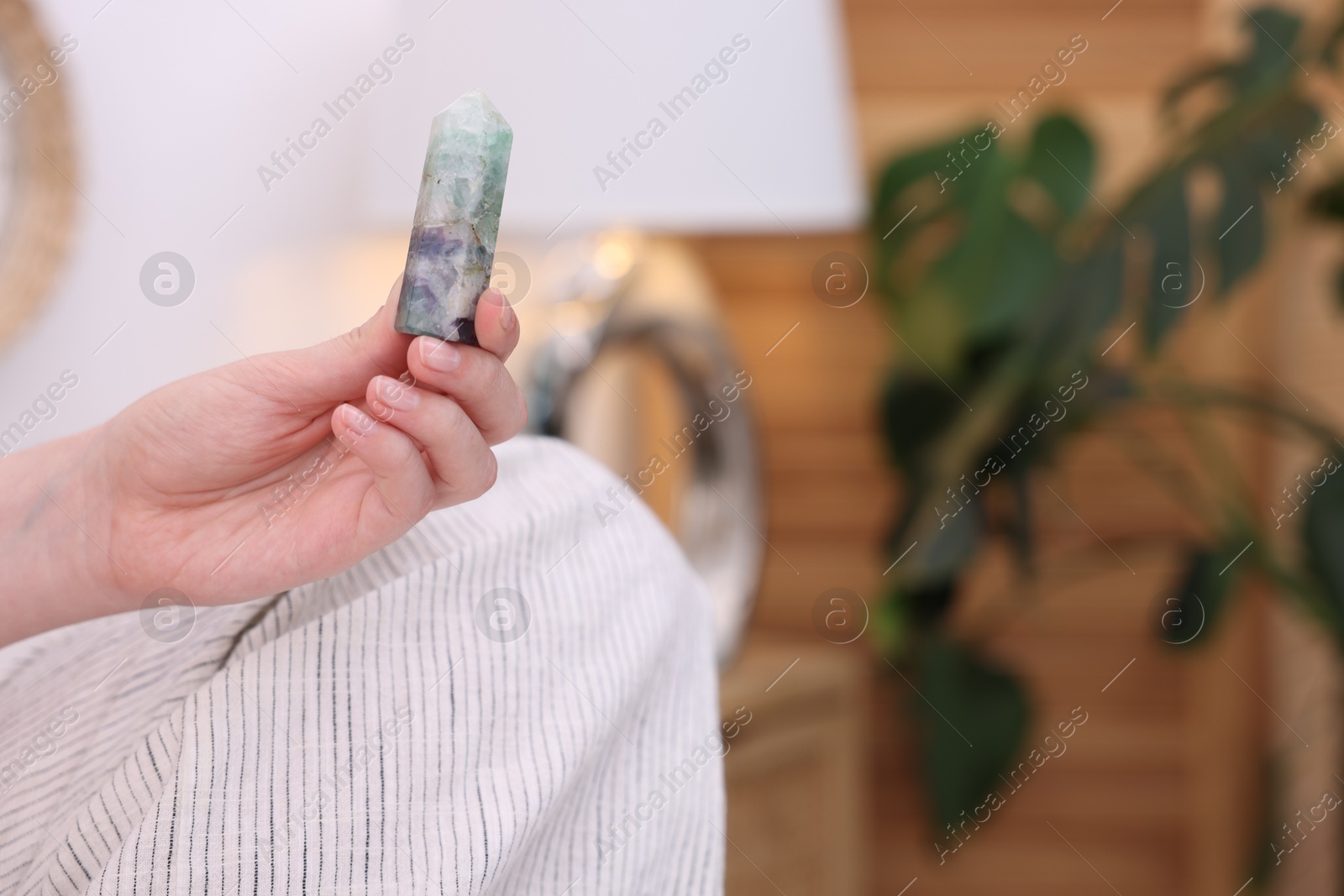 Photo of Woman with beautiful fluorite gemstone indoors, closeup. Space for text